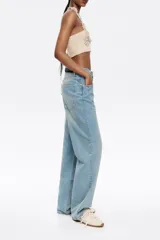 Pantalón vaquero celeste de corte wide leg, tiro bajo, con cierre frontal con botón denim y cinco bolsillos.