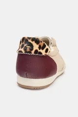 Zapatilla deportiva color beige con detalles en marrón y estampado animal print en el talón. Cierre con cordones y suela de 1,5 cm.