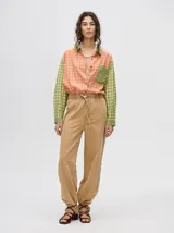 Mono largo de jean celeste con corte holgado, cintura elastizada con cordón ajustable, sin mangas, cuello camisero y cierre frontal con botones. Presenta bordados de motivos playeros en el pecho.