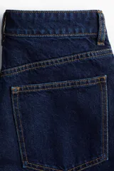 Bermuda de denim azul oscuro, de tiro alto y corte recto, con cinco bolsillos, cierre frontal con botón y trabillas para cinturón.