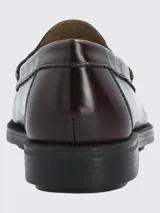 Zapato mocasín de cuero color borgoña con suela negra.