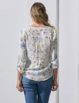 Blusa de gasa estampada con rayas verticales en tonos naranja, amarillo y blanco. Tiene cuello a la base, escote en V y botones. Delantera con bolsillo aplicado. Largo de manga regulable con presilla y botón. Terminación anudada opcional.