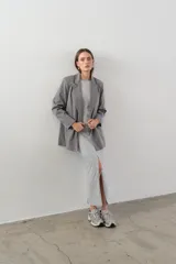 Blazer gris de corte clásico con solapas de muesca, cierre frontal con dos botones y bolsillos laterales con solapa.