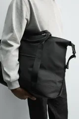 Bolso de viaje negro con acabado texturizado, compartimento principal con cierre de cremallera, bolsillo plano trasero con cierre de cremallera, banda de sujeción para equipaje y asa de hombro removible y ajustable.