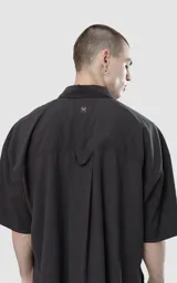 Camisa negra de manga corta con doble bolsillo ojal en delantero, realizada en tejido plano y silueta oversize.