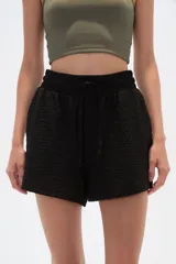Short negro con textura arrugada, cintura elástica con cordón ajustable y corte holgado.