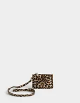 Monedero de cuerina con estampado animal print, correa lateral y aplique de tachas decorativas. Cuenta con cierre superior y correa lateral.