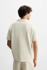 Polo manga corta a rayas horizontales color beige y blanco, con cuello solapa y cierre frontal de botonadura.