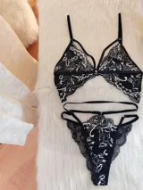 Conjunto de lencería negro con encaje bitono con detalles en color hueso. Incluye corpiño triangular de encaje con breteles ajustables y tanga con doble tira regulable en los laterales.