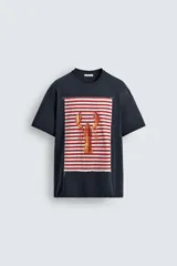 Camiseta azul marino de corte relaxed fit, cuello redondo y manga corta. Presenta un parche rectangular estampado con rayas horizontales rojas y blancas, y un dibujo de una langosta en el centro.