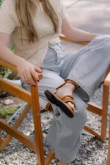 Sandalias bajas de cuero color marrón, con tiras finas para atar alrededor del tobillo.