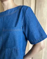 Remera negra con cuello redondo y mangas cortas, con detalle de pespuntes blancos en cuello, mangas, bolsillos frontales y ruedo.