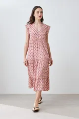 Maxi vestido de corte imperio, color rosa con estampado floral liberty en tonos fucsia. Tiene escote en V, mangas cortas con volados y falda larga con volantes. Cierre frontal con botones.