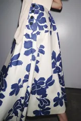 Falda midi de tiro medio confeccionada en hilatura de algodón, color blanco con estampado de flores azules. Cierre lateral con botones.