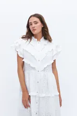 Vestido midi amarillo de lino, con volados en las mangas y detalle de volados y botones a lo largo del frente. Presenta un corte con talle marcado y falda escalonada.