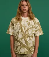 Remera de algodón color crudo con estampado de ramas y hojas en tonos marrones. Corte boxy, cuello redondo y mangas cortas.