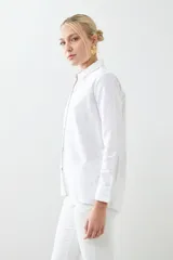 Camisa blanca de manga larga con cuello clásico y cierre frontal con botones.