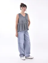 Blusa blanca sin mangas con escote en V y cierre frontal con botones.