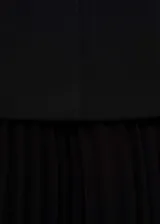 Vestido negro con cuello halter y falda plisada.