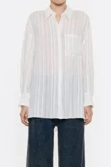 Camisa larga de viscosa con textura, de corte recto, con cuello camisero, manga larga de puño con botón y cierre frontal con abotonadura. Presenta bolsillo de plastrón en el pecho y nudo decorativo en la parte trasera para dar volumen.