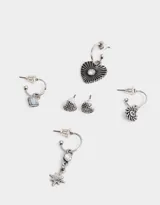 Set de aros plateados con dijes de corazón, sol, estrella y piedra. Incluye aros tipo botón con diseño de corazón.