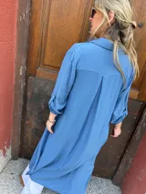Sobrecamisa larga azul de viscosa con cuello camisero, manga larga con puños abotonados y tajos laterales.