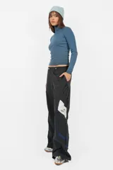 Pantalón deportivo gris de nylon, de calce recto y tiro medio, con elástico en la cintura, cordones ajustables y detalle de recorte con vivo a contratono en los laterales.