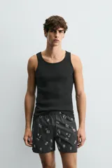 Bañador negro con estampado de dibujos en blanco. Tiene cintura elástica ajustable con cordón, bolsillos laterales y trasero.