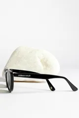 Lentes de sol estilo ojo de gato, montura negra brillante y lentes oscuros polarizados.