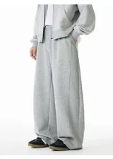 Pantalón de jogging gris de algodón, corte ancho (baggy) y tiro alto, con costura central vertical que recorre la pierna.