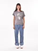 Remera negra de algodón con estampado frontal de la palabra "MERCI" en letras delineadas con colores del arcoíris.