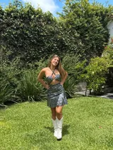 Vestido corto con estampado de rayas horizontales en tonos grises y negros. Diseño con escote halter que se ata al cuello, abertura central en el busto y falda corta con volado.