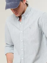 Camisa de vestir a rayas verticales azules y blancas, corte slim fit, con cuello abotonado y logo bordado en el pecho.
