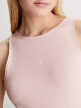 Vestido corto de punto milano color rosa pálido, de corte ajustado y sin mangas. Presenta espalda deportiva con panel recortado, cremallera lateral oculta y logo monograma de Calvin Klein estampado en el pecho.