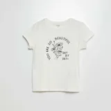 Camiseta blanca de punto con cuello redondo y mangas cortas. Estampado frontal con flores y texto en color negro.