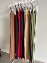Vestido largo de viscosa, con breteles finos y escote en V. Presenta un diseño acanalado o de punto, disponible en varios colores como marrón, negro, rojo, azul marino, beige y verde oliva.