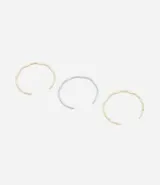 Set de tres brazaletes rígidos de metal con efecto arrugado, uno dorado, uno plateado y uno bicolor.