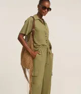 Pantalón largo color verde oliva, de malla orly, modelo pijama, con cintura elástica, lazo en la cintura y bolsillos cargo en los laterales.