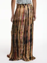 Pantalón de tiro alto con estampado tie-dye en tonos marrón, negro y rosa. Tiene pretina elástica ajustable con lazo, bolsillos laterales y corte palazzo.