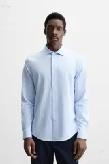 Camisa celeste a rayas verticales blancas, de corte recto, con cuello italiano abierto, manga larga con puños abotonados y cierre frontal con botones.