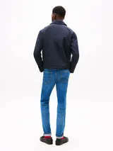 Campera azul marino de poliéster con cuello inglés, cierre frontal de cremallera, dos bolsillos laterales con cremallera y puños con cierre a presión. Presenta un logo de Tommy Hilfiger bordado en el pecho.