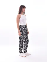 Pantalón babucha de tela estampada con hojas en tonos rosa, naranja y azul, con cintura elastizada y lazo para ajustar.