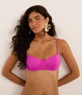 Top de bikini fucsia, modelo media taza con aro, lazo en la espalda y breteles adornados con adornos y nuditos.