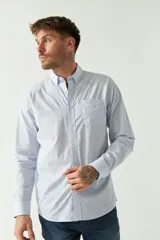 Camisa celeste a rayas rojas de hombre, manga larga, con bolsillo y logo bordado.