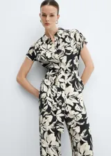 Mono largo de viscosa color crema con estampado floral fucsia, cuello camisero, manga corta, dos bolsillos laterales, trabillas y cinturón con lazo.