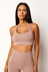 Top deportivo color rosa nude, con breteles anchos y espalda tipo nadador. Confeccionado con tecnología seamless y textura acanalada. Incluye forro y apertura para almohadillas.