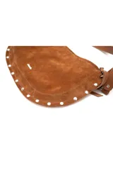 Cartera de gamuza color marrón, de tamaño mediano y forma curva. Posee una correa ajustable y detalles de pequeñas tachuelas metálicas en el borde inferior.