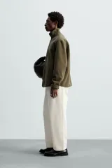 Sobrecamisa verde militar de tejido polar, corte regular fit, cuello alto, manga larga, bolsillos laterales y cierre frontal con cremallera.