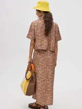 Camisa corta color marrón con estampado floral en tonos lila, de mangas cortas y cuello camisero.