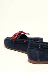 Mocasín tipo boat shoe con estampado de vaca en tonos marrón y blanco, confeccionado en cuero. Cuenta con cordones de cuero marrón oscuro y suela de goma.